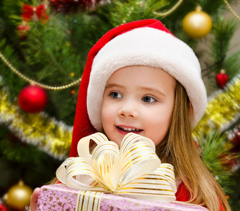 可爱的小女孩，在圣诞老人的帽子，带着礼物