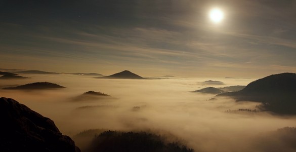 月圆之夜与日出的美丽的山波西米亚萨克森州瑞士。砂岩山峰和丘陵，从模糊背景增加，雾是橙色，由于太阳光线