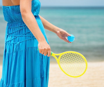 在海滩上玩网球的蓝裙子的女人