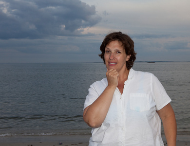 幸福的女人，穿着白衬衫在阴天的时候沙滩上