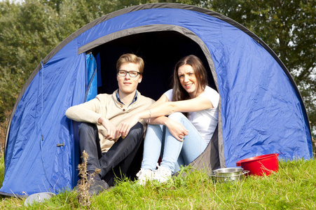 年轻的男人和女人与蓝色帐篷露营