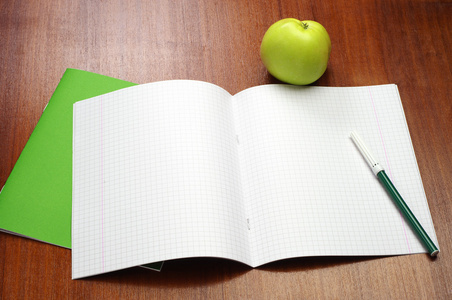 打开的学校笔记本 签字笔和苹果