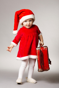 可爱的小女孩带着圣诞小提箱