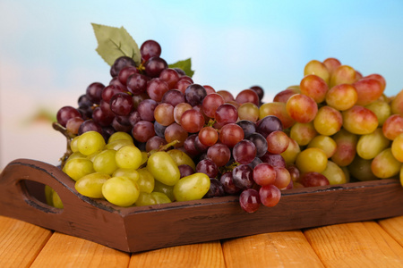 在明亮的背景上的木托盘上的新鲜葡萄