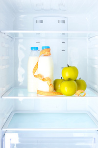 饮食概念照片 苹果和牛奶瓶与测量类型在架子上的冰箱