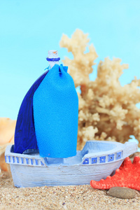 在沙子上，蓝色背景上的蓝色玩具船