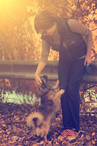 女人与她的狗在秋天的公园里的旧照片