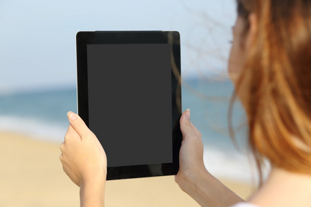 一个女人在沙滩上显示一个空白的平板电脑屏幕的特写