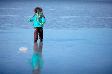 可爱的小男孩在外面玩在冰冻的海面上