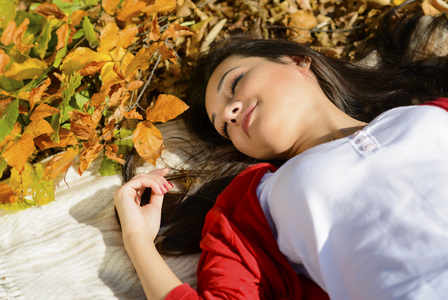 年轻漂亮的女人放松在秋天的公园