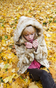 美丽的女孩温暖冰冻的手，在秋天的公园