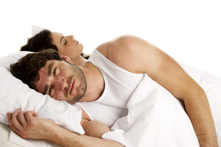 男子躺在白色的床旁边熟睡中的女人