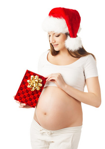 在圣诞老人的帽子，拿着礼物礼物盒的孕妇。孤立的白色背景