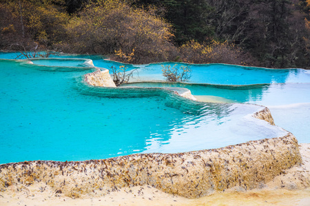 蓝色的露天钙华彩池在黄龙照片