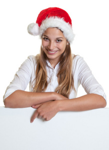 指向在广告牌上的圣诞帽的年轻女子