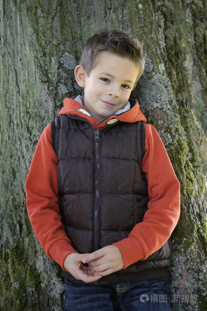 害羞的小男孩,斜靠在一棵树
