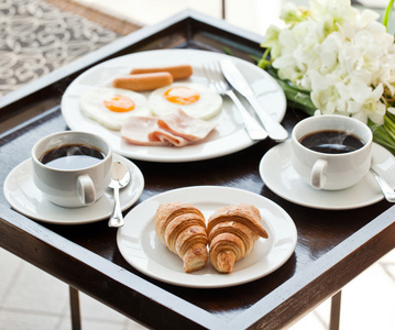 与杯黑咖啡，鸡蛋和羊角面包在阳台上吃早餐