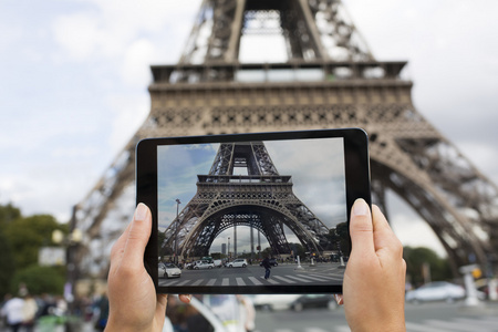 女人在巴黎埃菲尔铁塔的用她的手机拍照
