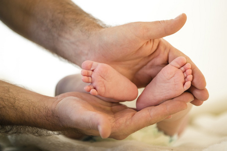 父亲抱小宝宝用推广的脚趾的脚双手