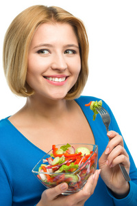 年轻漂亮的女性吃沙拉使用餐叉