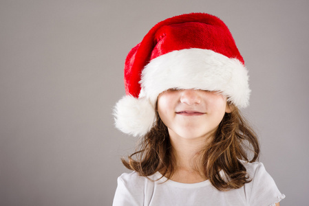 与圣诞礼物圣诞老人的帽子的小女孩