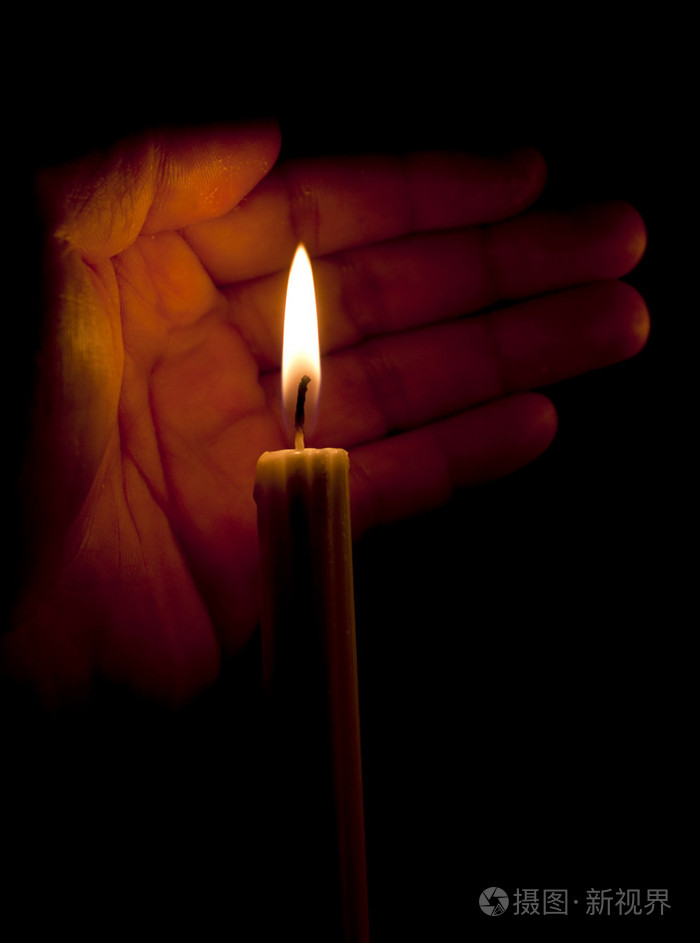 人的手掌和一支蜡烛在黑暗中