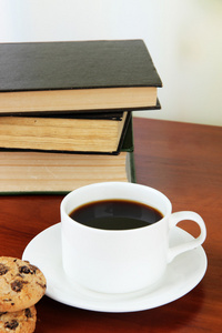 杯咖啡以饼干，在明亮的背景上的木桌子上的书