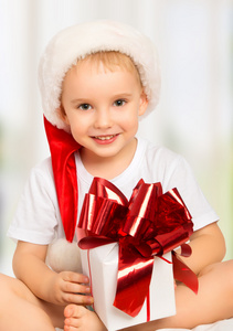 可爱的孩子在一件礼物的圣诞帽子的小男孩
