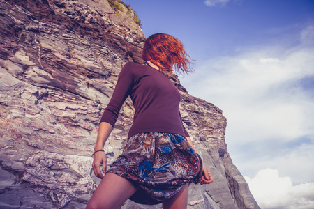 年轻女子在裙站在旁边的岩石