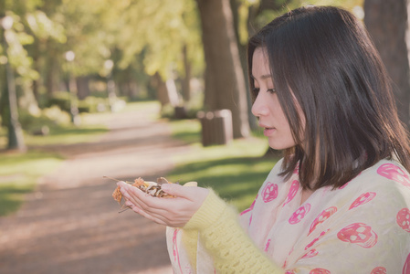 女人抱着树叶在公园里