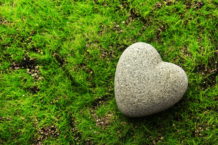 灰色的石头在心脏的形状，在草地上的背景