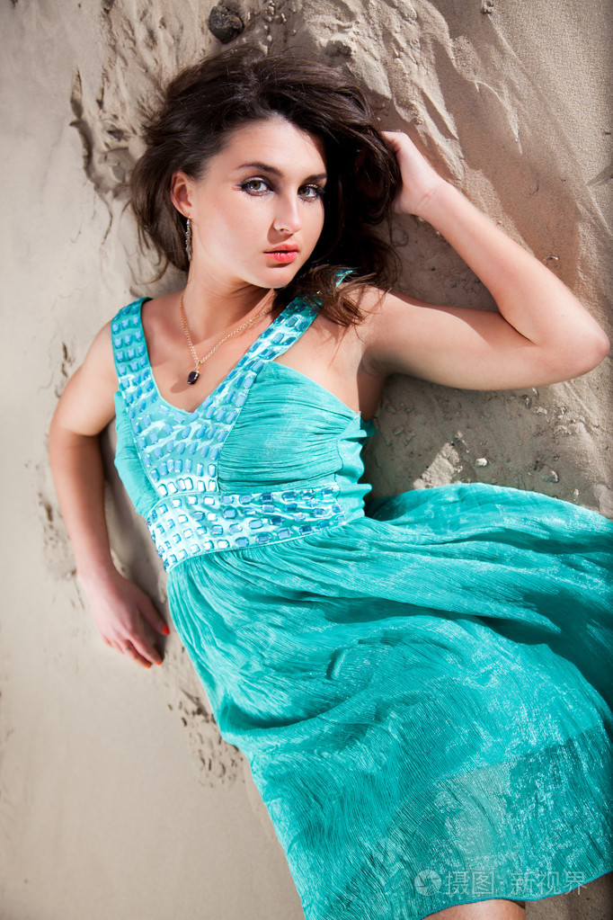 优雅的土耳其妇女,穿着蓝色的衣服,躺在沙丘上