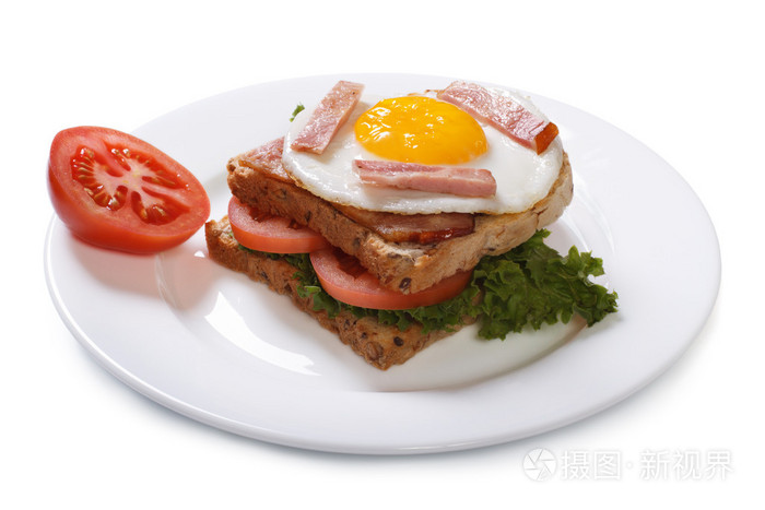 三明治配一个煎的鸡蛋和番茄为孤立的早餐