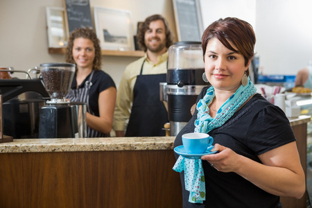 Customer Holding Coffee Cup With Workers At Caf