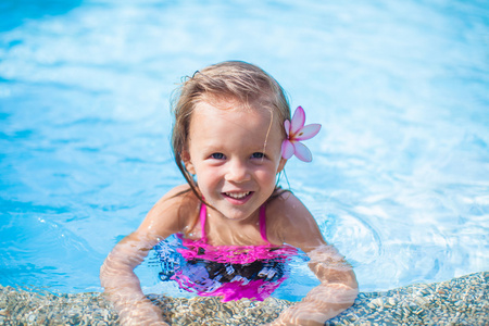 可爱的小女孩在游泳池里她耳朵后面的花