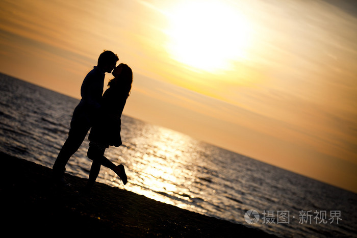 在日落时分在沙滩上亲吻的恋人