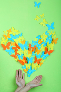 绿墙背景上的手上的纸蝴蝶