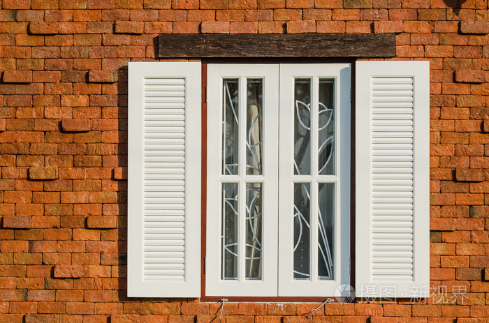 棕色木制窗户上砖墙壁在阳光灿烂的日子