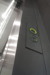 绿色照明的电梯按钮及玻璃和铝合金门开口