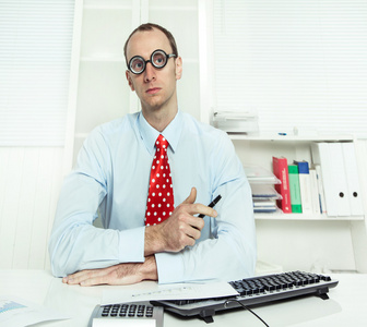 傲慢自大的人坐在办公桌前着眼镜，一条红领带，一件蓝色衬衫