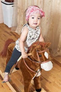 小女孩骑着匹马玩具