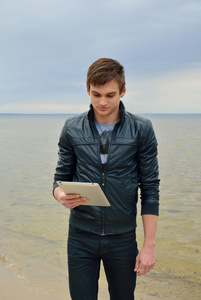 这位年轻人正在看在一款平板电脑在海