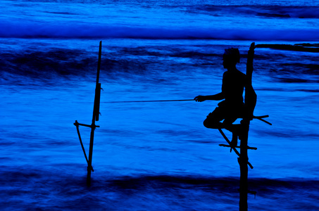 在斯里兰卡,一个当地的渔夫晚上垂钓,以独特的风格照片