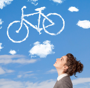 年轻的女孩低头看自行车在蓝蓝的天空上的云