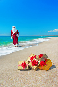 圣诞老人与海海滩上放松的很多黄金礼品