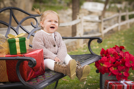 年轻的小孩孩子坐在长椅上与圣诞礼物无惧