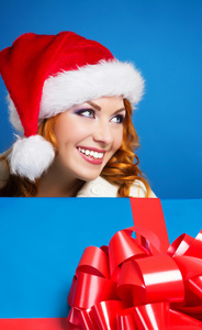 一个幸福的女人，在蓝色背景上的红色圣诞帽子