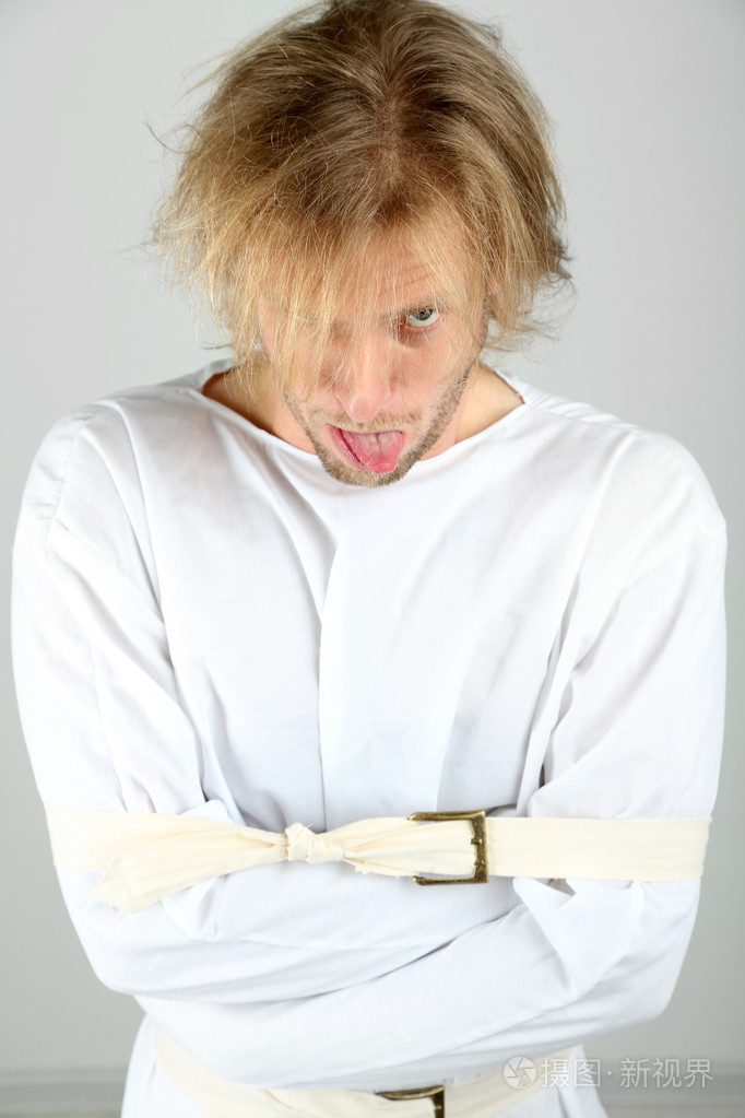 精神病的男子在灰色背景的海峡夹克