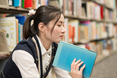 女人拿着一本书靠近书架