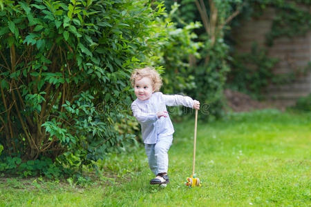 可爱的小女孩在花园里拿着木制玩具